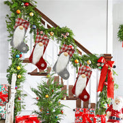 ELITE CASA Christmas stockings hanging on a decorated staircase with festive garlands and gifts.